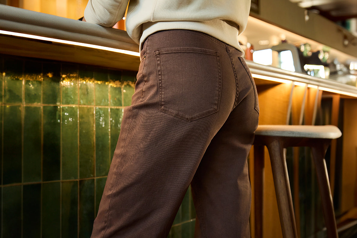  A woman standing at a bar wearing brown pants