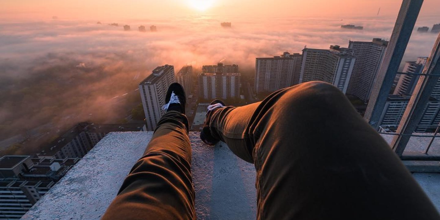 a man wearing DUER jeans lying down on top of a building watching a sunset