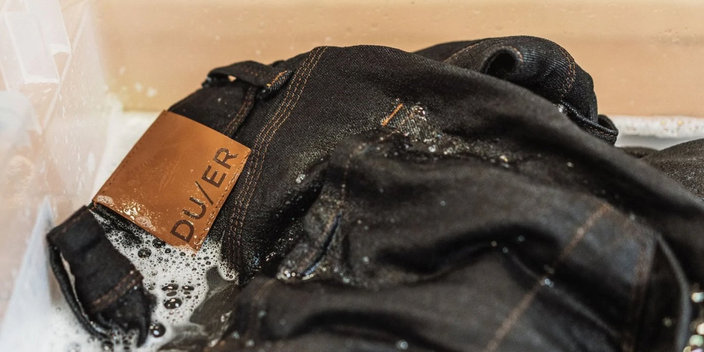 a pair of black DUER jeans being washed