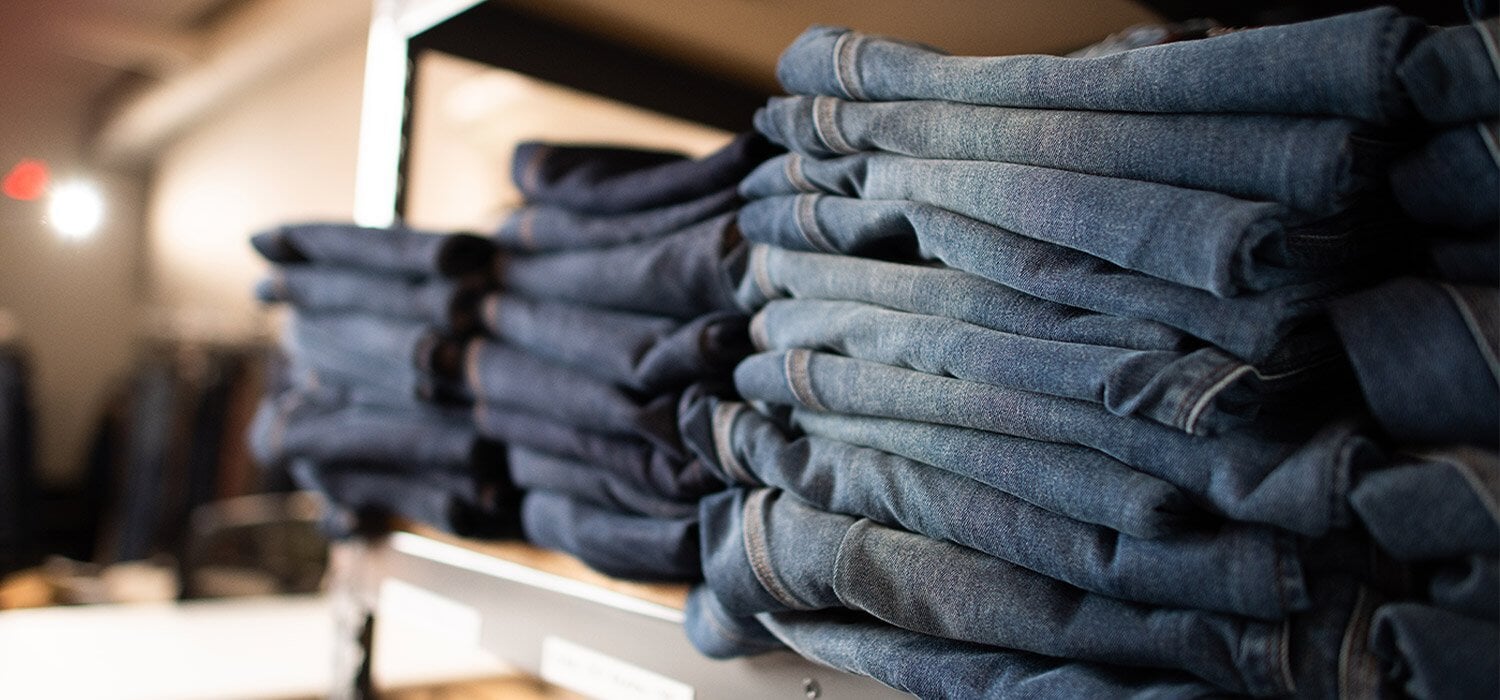 Multiple pairs of denim jeans stacked on a shelf
