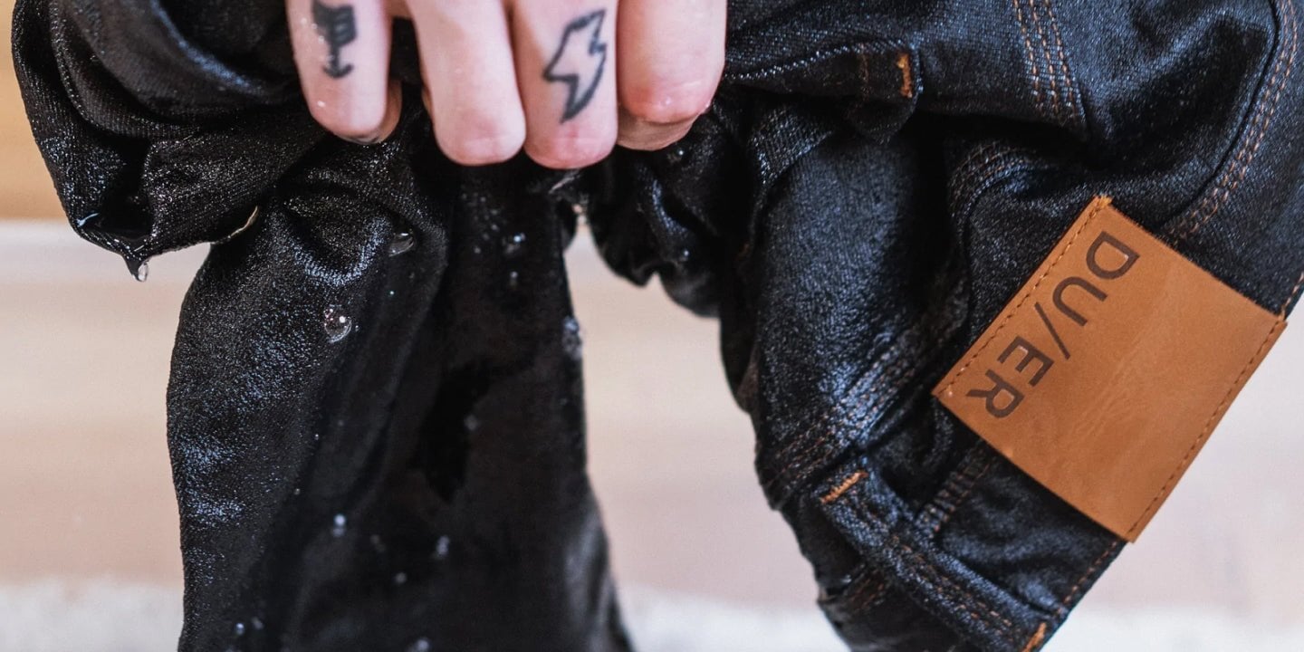 person holding a soaking wet pair of DUER denim