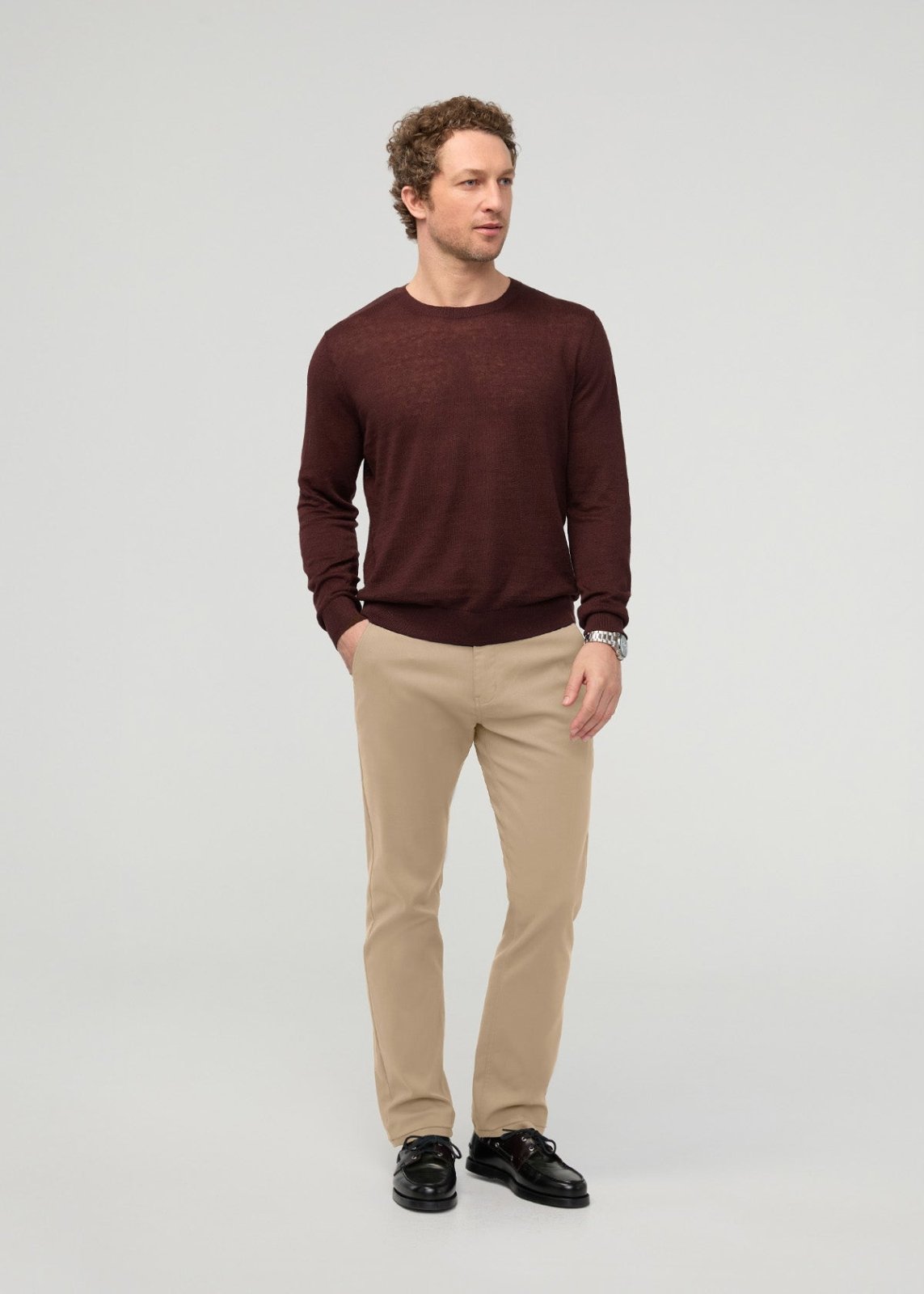 Man wearing dark burgundy crew neck sweater and khaki slim straight trousers with black shoes.