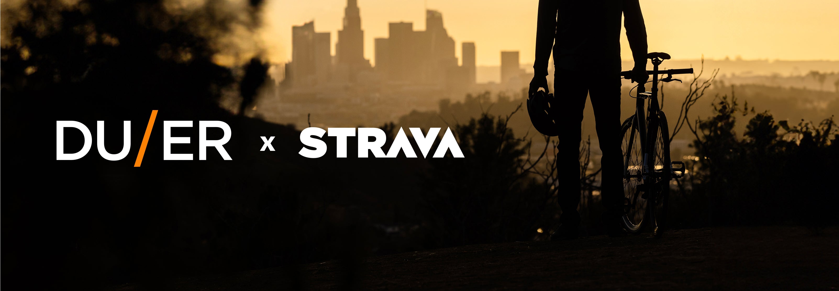 Silhouette of man with bike overlooking city skyline, with 'DUER x STRAVA' text overlaid.