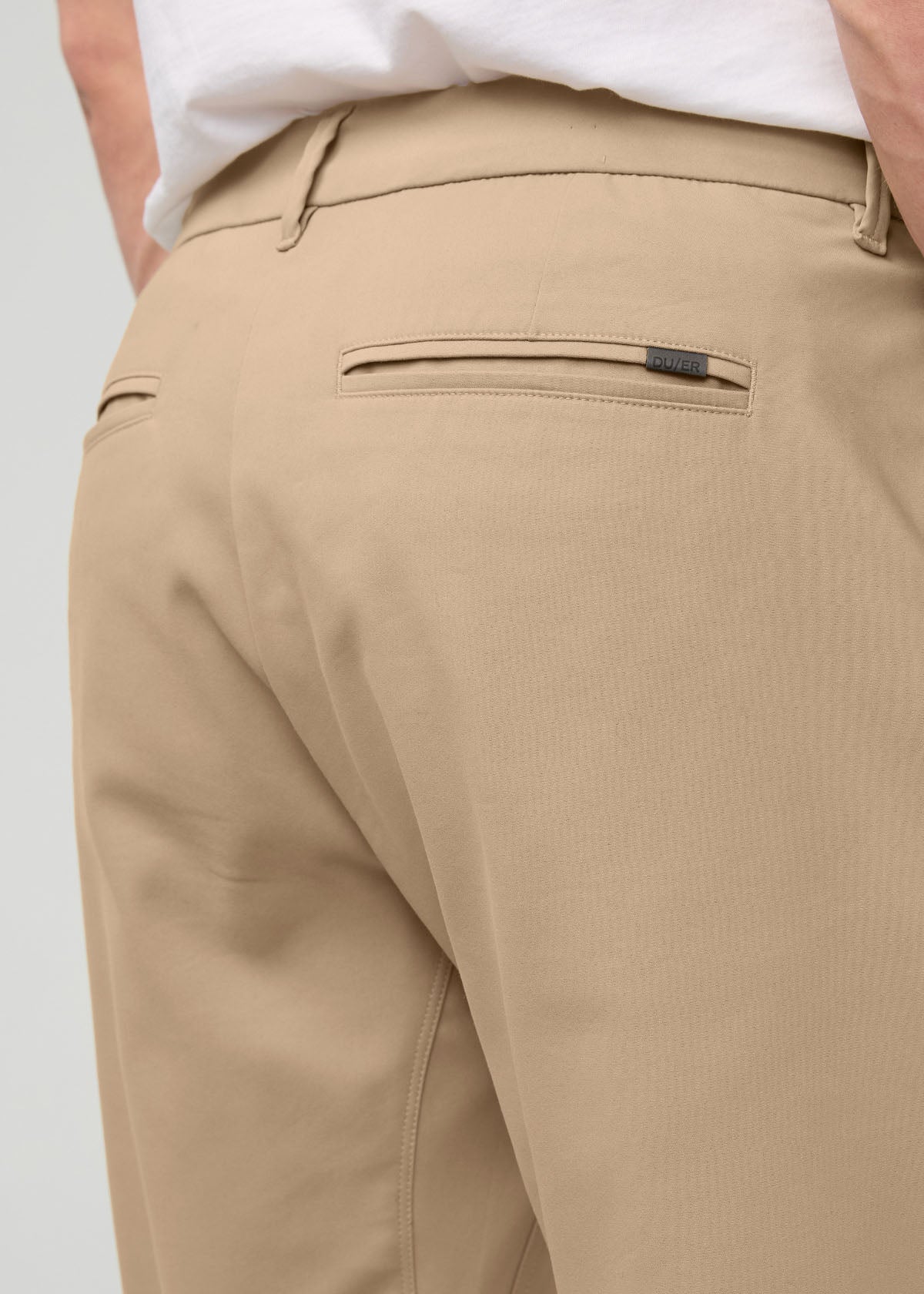 Desert khaki relaxed taper trouser with front pockets and belt loops, worn with white shirt.