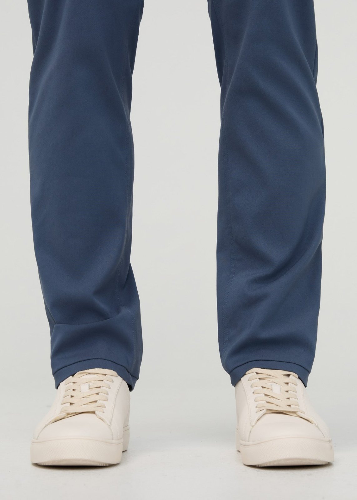 Dark blue relaxed taper trousers with tapered ankles, styled with cream platform sneakers.