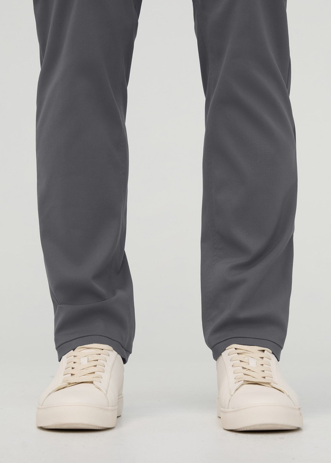 Gray relaxed taper trousers tapered at ankles, worn with cream lace-up sneakers.