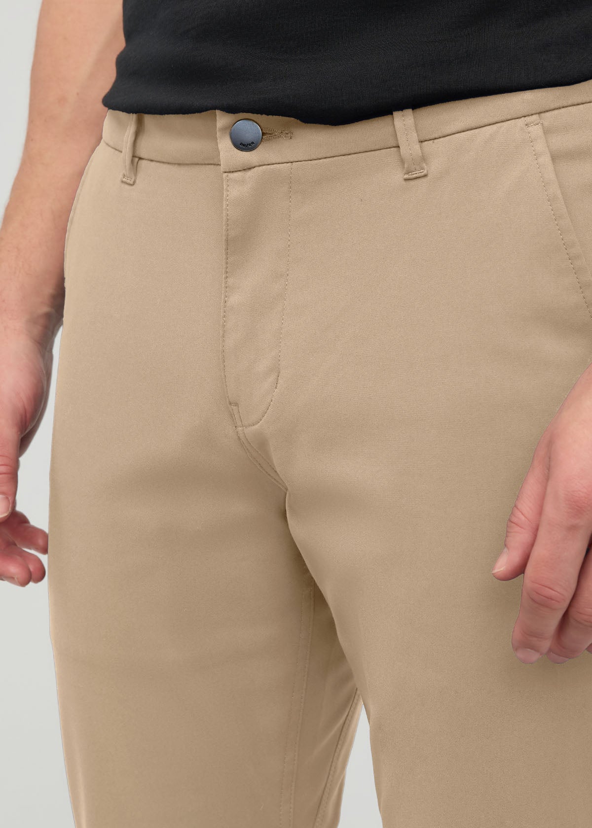 Desert khaki slim straight trousers with metal button closure and belt loops, worn with black shirt.