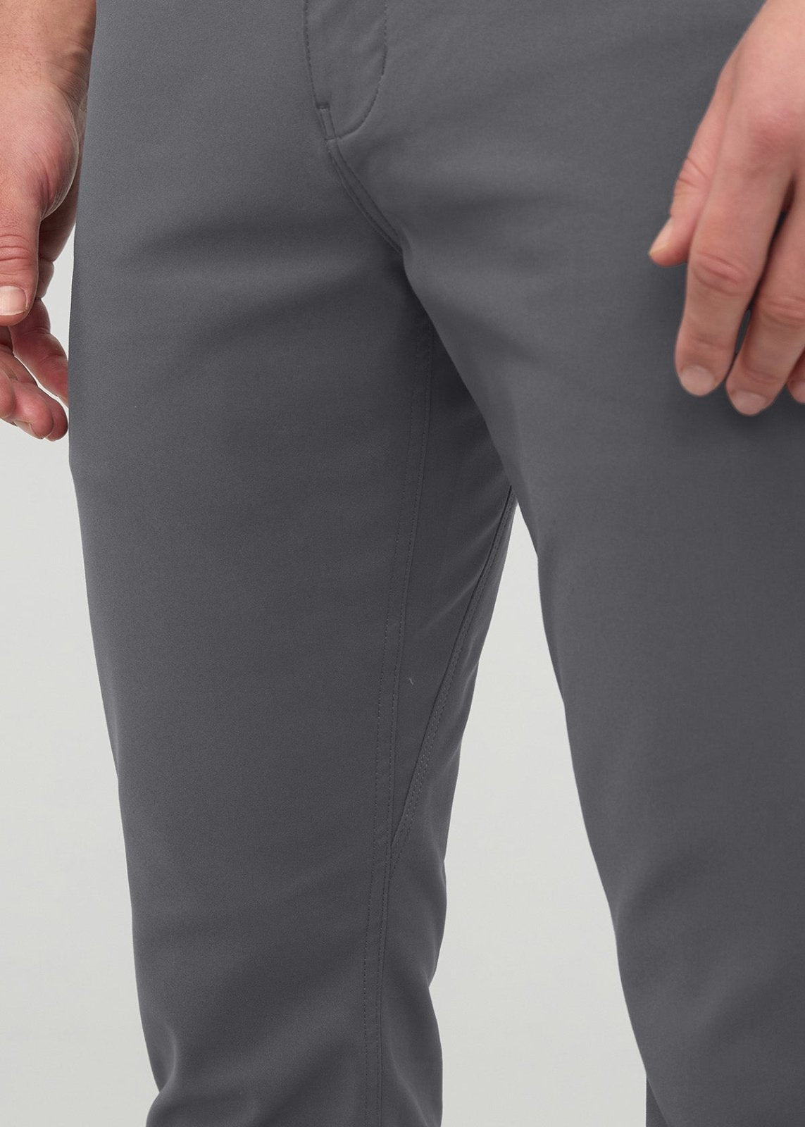 Gray slim straight trousers with flat front waistband and seam details, worn by a person against a white background.