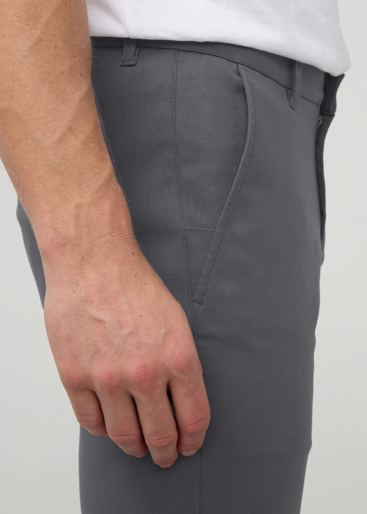 Dark gray slim straight trousers with flat front and button closure, worn with white shirt.