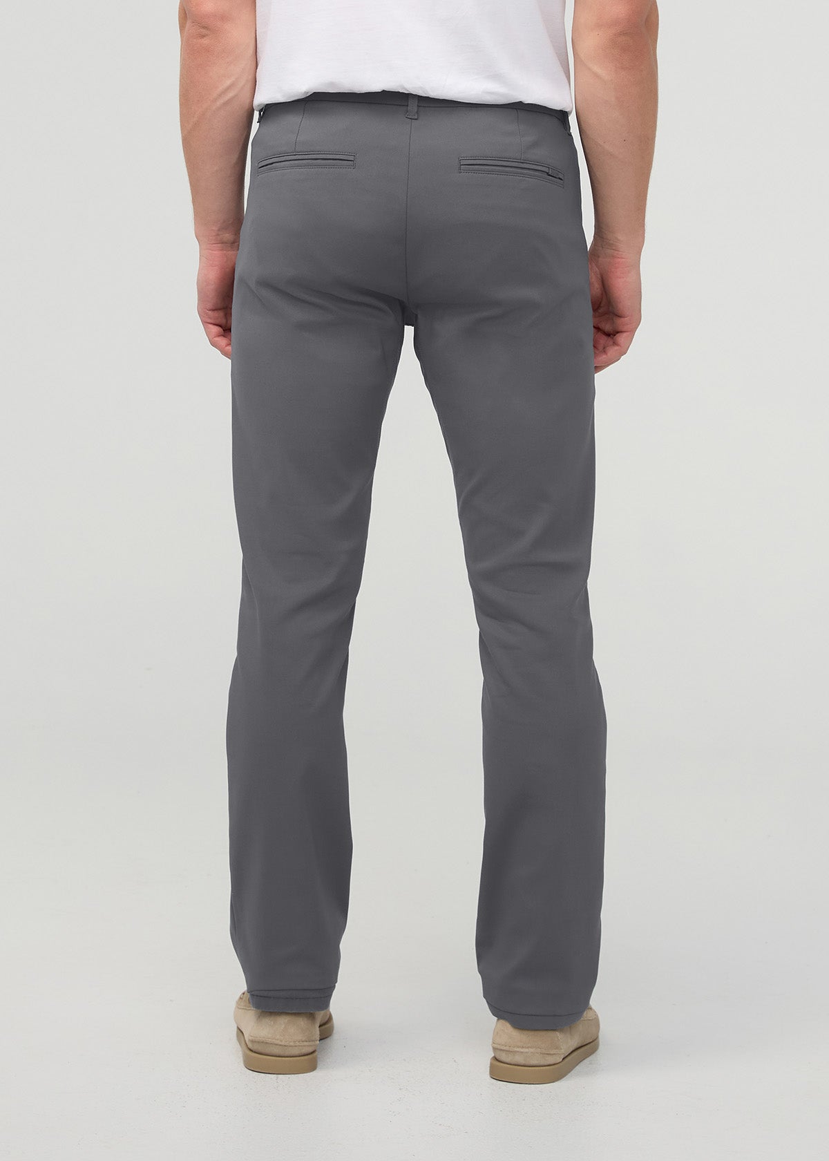 Man wearing gray slim straight trousers with white shirt, viewed from behind.
