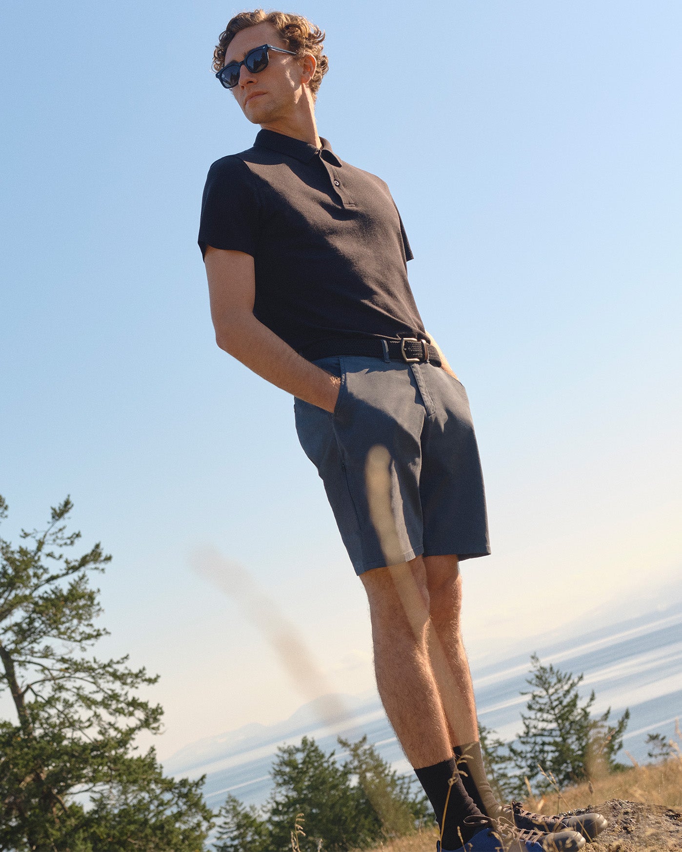 man with sunglass standing by ocean wearing DUER shorts 