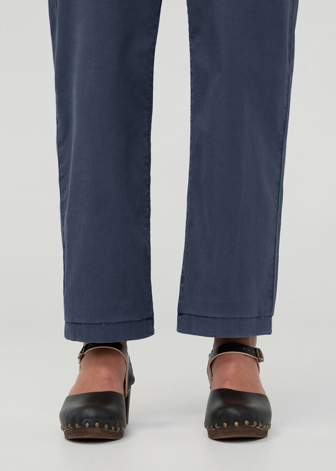 Navy blue boiler suit pants with cuffed hems and black studded clogs with ankle straps.