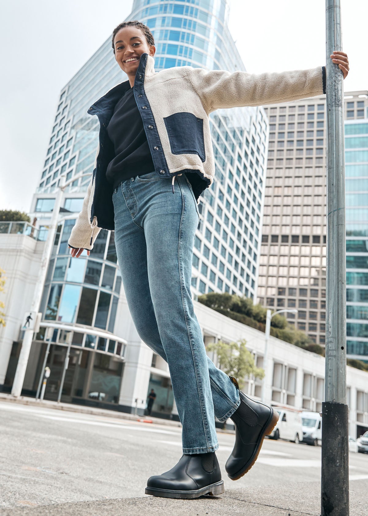 woman hanging on street post wearing vintage blue high rise straight stretch jeans